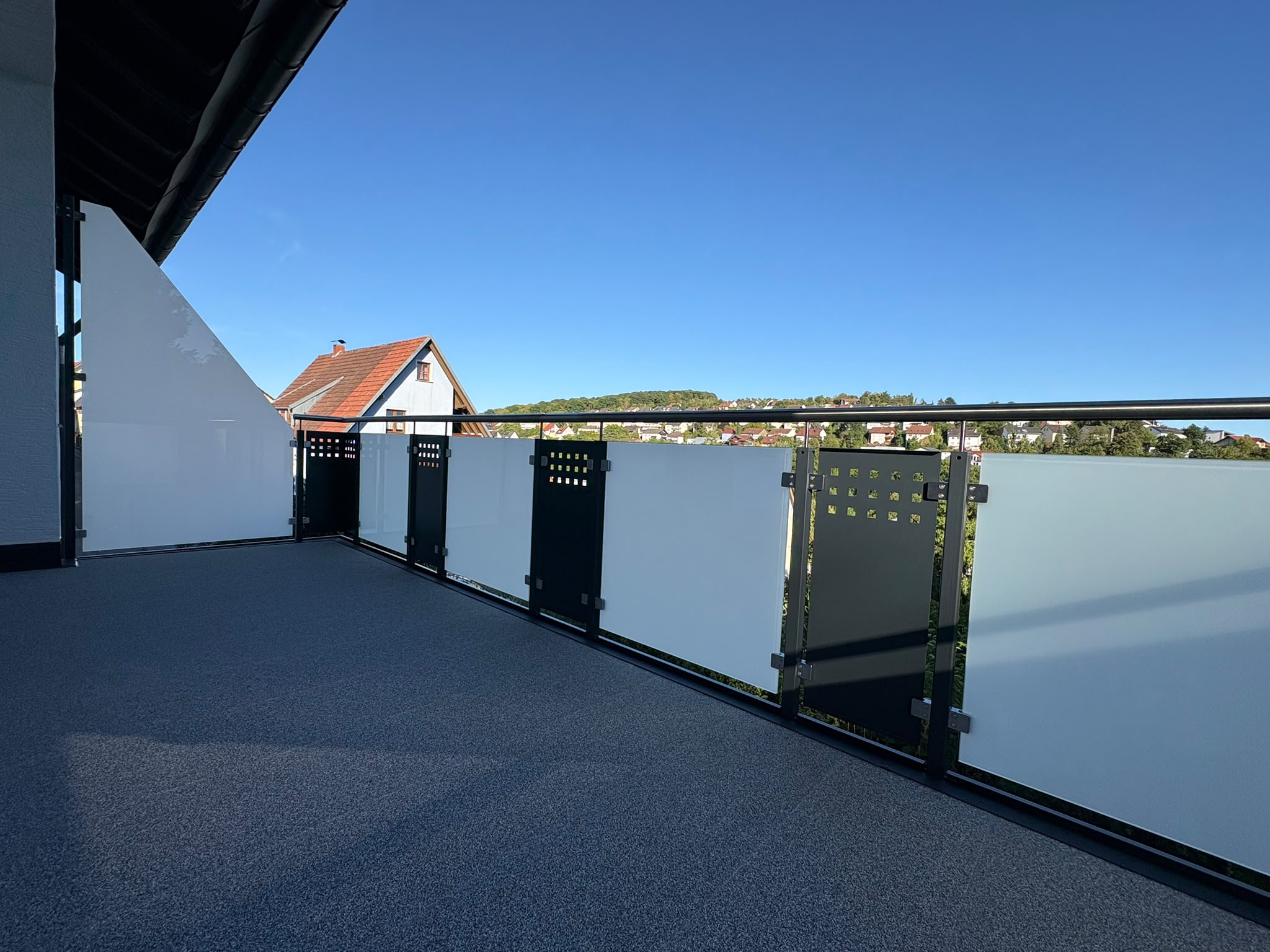 Sanierter Balkon mit Steinteppich-Boden und Glasgelaender